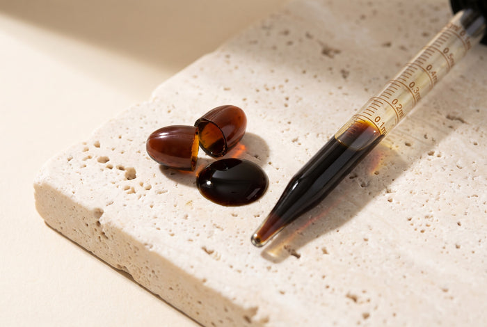 A cut softgel beside a graduated pipette holding the oil