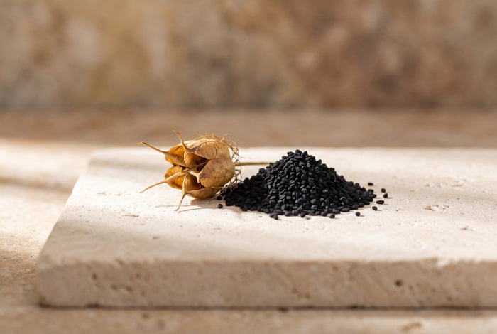 A split nigella seed pod beside one mound of black seeds